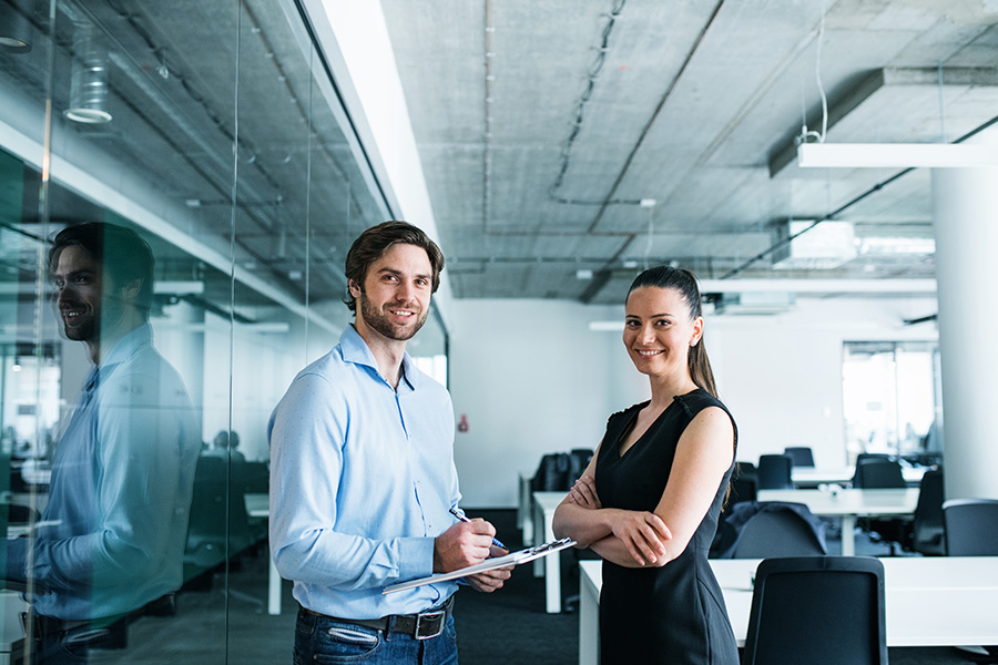 Young businesspeople with clipboard standing in an office, working.