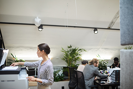 Side view portrait of young businesswoman scanning documents while working in office, copy space