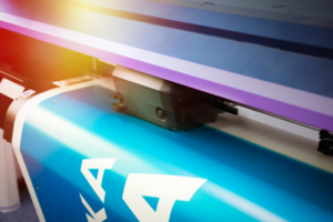 Close-up of a large format printer in operation, producing a colorful print. Large Format Printer used for high-quality wide-format printing.