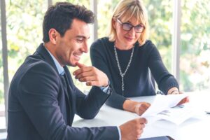 Two business professionals reviewing documents together at a desk, discussing copier lease options for their office to optimize printing solutions.